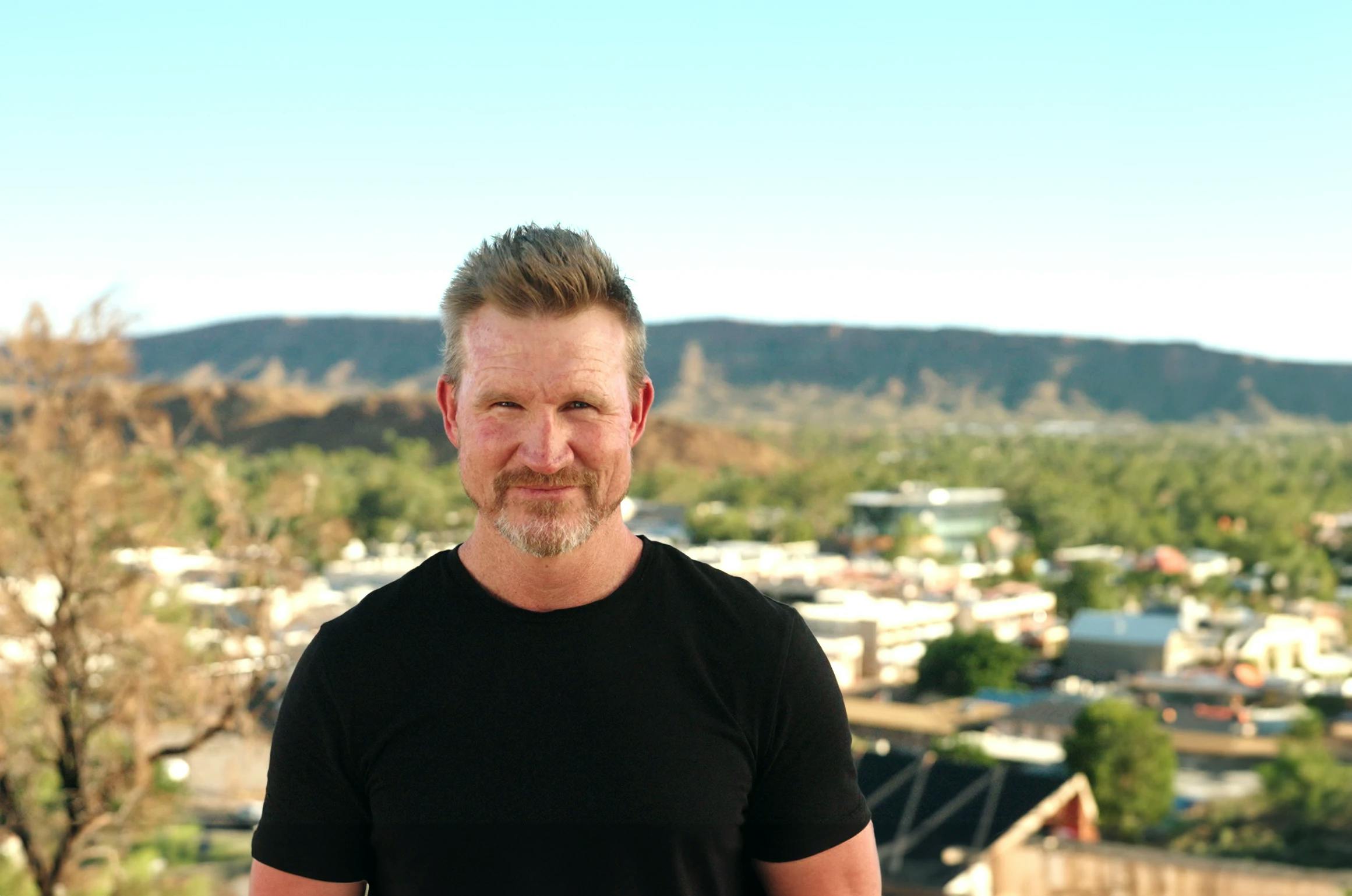Nathan Buckley standing in front of a scenic view of Alice Springs